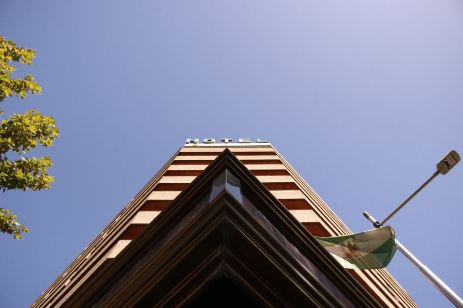 A low-angle view of a hotel building with a clear blue sky, capturing urban architecture.