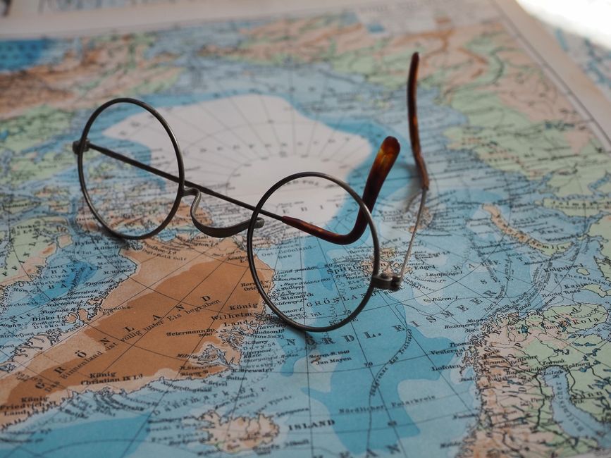 Vintage round glasses on a detailed world map, showing Europe and Greenland.