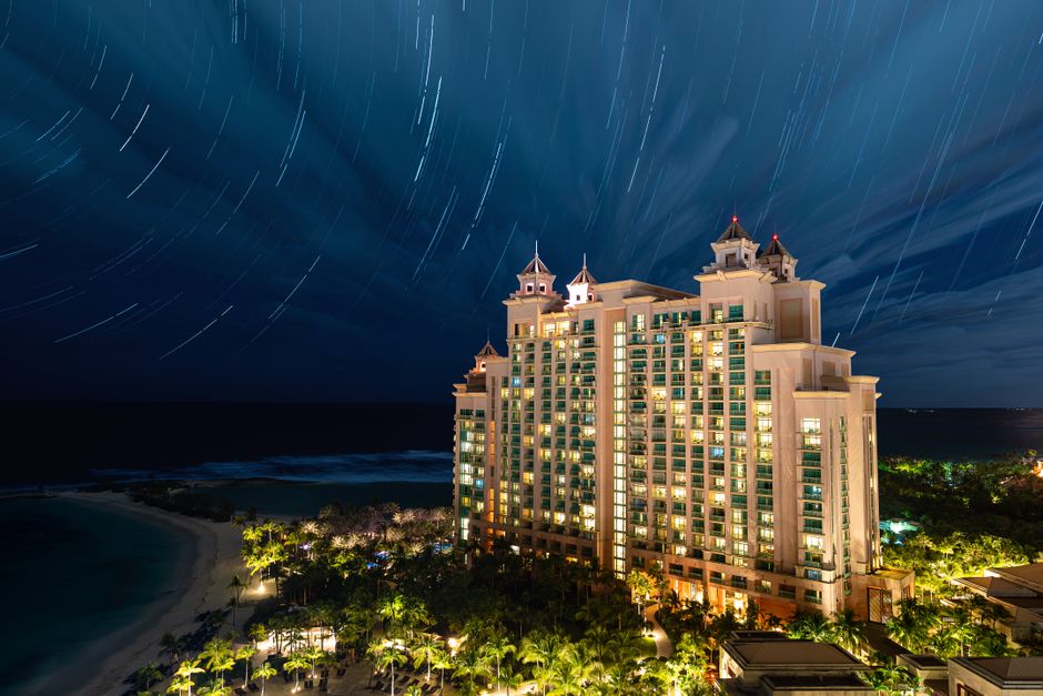 A luxurious beachfront hotel with stunning circular star trails in the night sky.