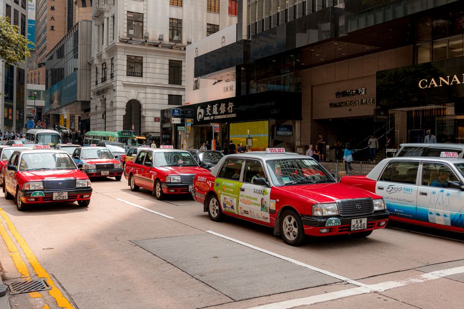 Bustling city street with red taxis and busy shops in downtown on a sunny day.